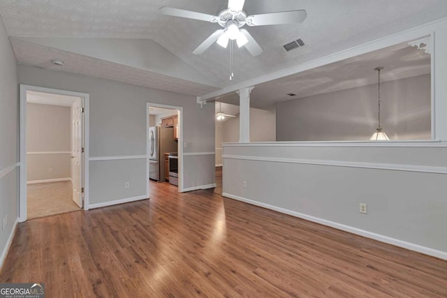 interior space with stainless steel fridge, ensuite bath, a textured ceiling, wood-type flooring, and lofted ceiling