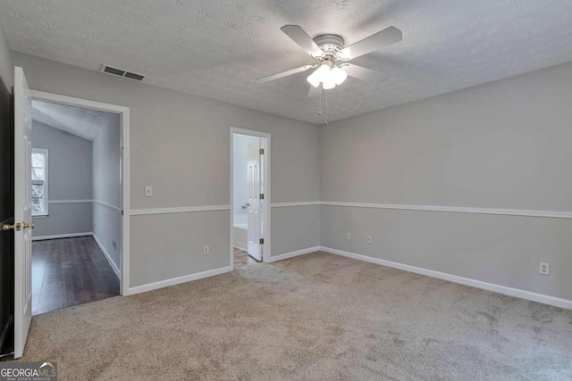 carpeted spare room featuring a textured ceiling, ceiling fan, and vaulted ceiling