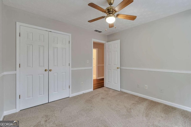 unfurnished bedroom with light carpet, a textured ceiling, a closet, and ceiling fan