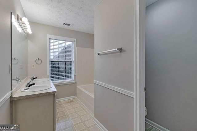 bathroom featuring vanity, toilet, a textured ceiling, and a washtub