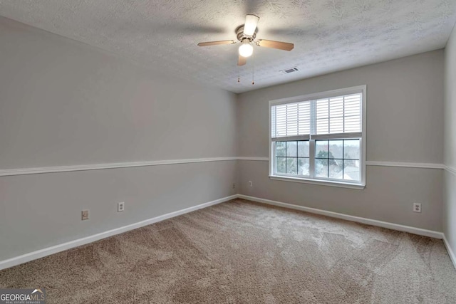 carpeted empty room with ceiling fan and a textured ceiling