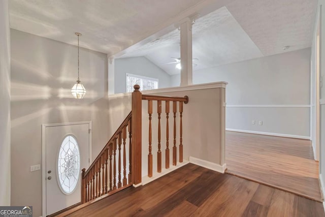 stairs with plenty of natural light, hardwood / wood-style floors, a textured ceiling, and lofted ceiling