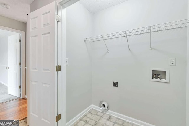 laundry room with hookup for a washing machine, a textured ceiling, light hardwood / wood-style flooring, and electric dryer hookup