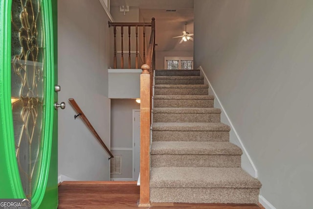 staircase with ceiling fan and wood-type flooring