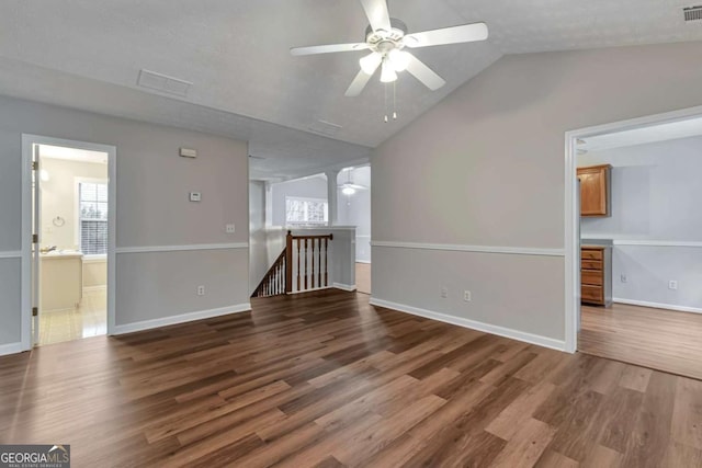 unfurnished living room featuring ceiling fan, dark hardwood / wood-style flooring, lofted ceiling, and a textured ceiling