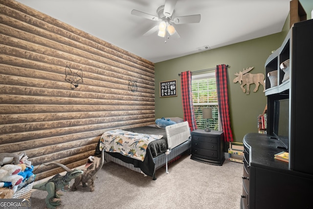 carpeted bedroom with rustic walls and ceiling fan