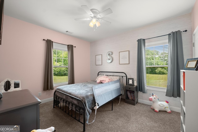 bedroom with multiple windows, dark colored carpet, and ceiling fan