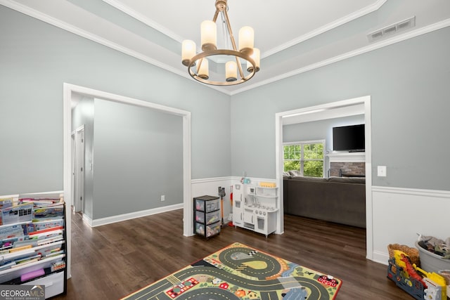 interior space featuring a stone fireplace, crown molding, dark hardwood / wood-style floors, and an inviting chandelier