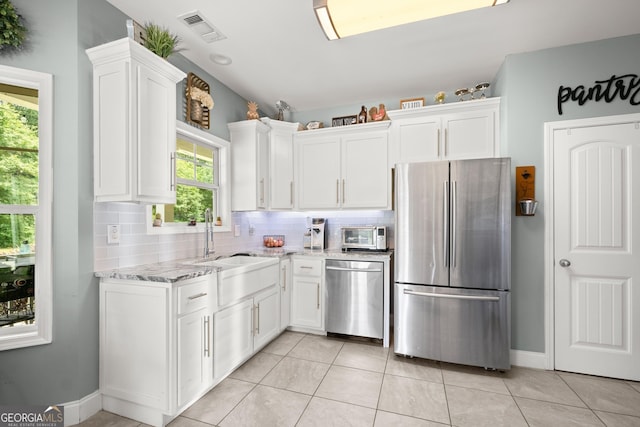 kitchen featuring white cabinets, sink, light stone countertops, light tile patterned flooring, and stainless steel appliances