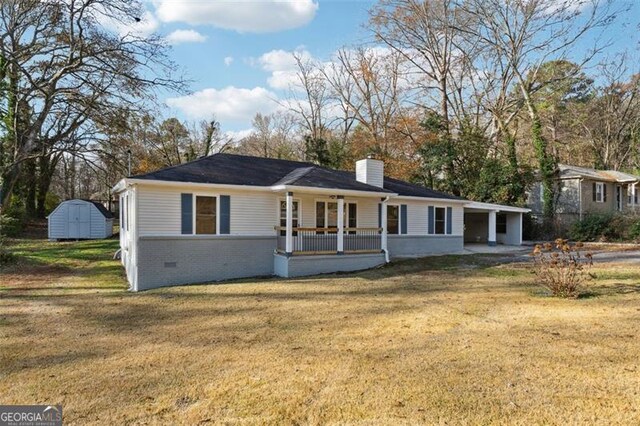 ranch-style home with a front yard, a shed, a carport, and covered porch