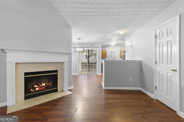 unfurnished living room with a chandelier, a textured ceiling, and dark wood-type flooring