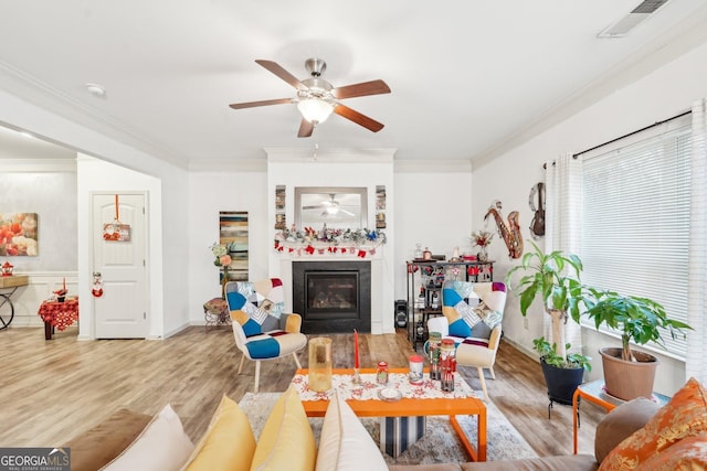 living room with ceiling fan, crown molding, and light hardwood / wood-style flooring