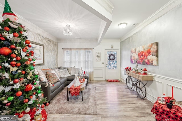 living room with light hardwood / wood-style floors, an inviting chandelier, and ornamental molding