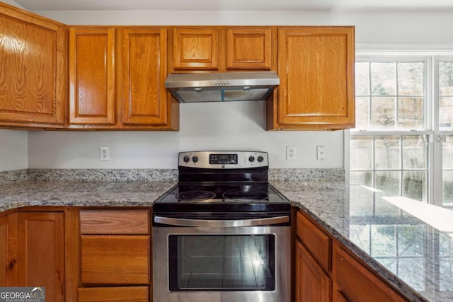 kitchen with electric stove, light stone countertops, and exhaust hood