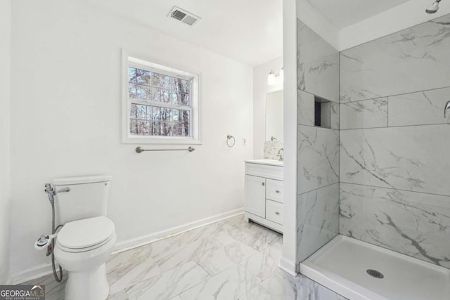 bathroom featuring a tile shower, vanity, and toilet