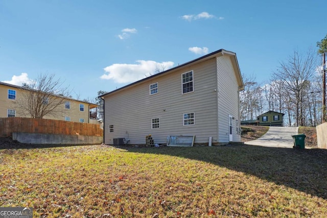 rear view of house featuring central air condition unit and a lawn