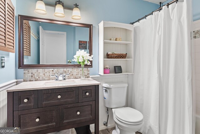 bathroom with decorative backsplash, a shower with curtain, vanity, and toilet