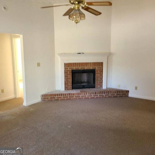 unfurnished living room featuring carpet, a brick fireplace, and ceiling fan