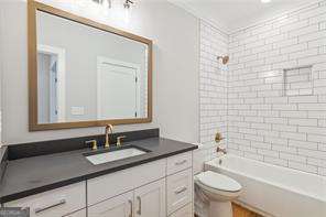 full bathroom featuring tiled shower / bath combo, vanity, and toilet