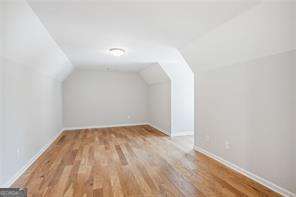 additional living space with wood-type flooring and lofted ceiling