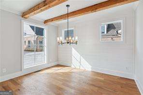 unfurnished dining area with wood-type flooring, beam ceiling, and a chandelier