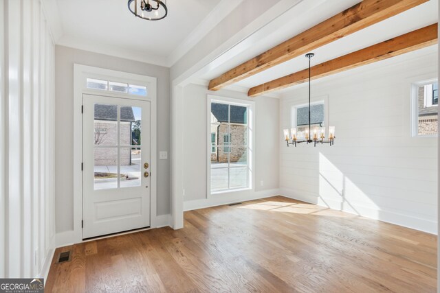 unfurnished dining area featuring hardwood / wood-style floors, beamed ceiling, and an inviting chandelier