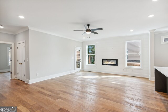 unfurnished bedroom featuring crown molding, a walk in closet, hardwood / wood-style flooring, a closet, and ceiling fan