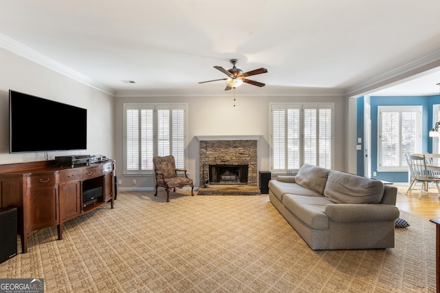 living room featuring crown molding, a wealth of natural light, ceiling fan, and a fireplace