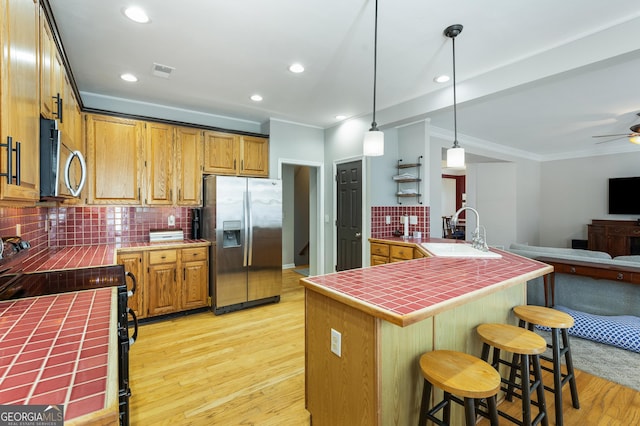 kitchen featuring appliances with stainless steel finishes, tile countertops, sink, hanging light fixtures, and kitchen peninsula