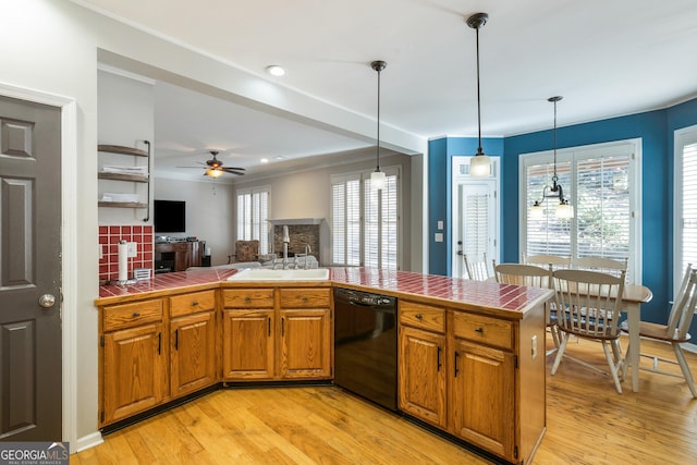 kitchen featuring tile countertops, pendant lighting, a wealth of natural light, dishwasher, and sink