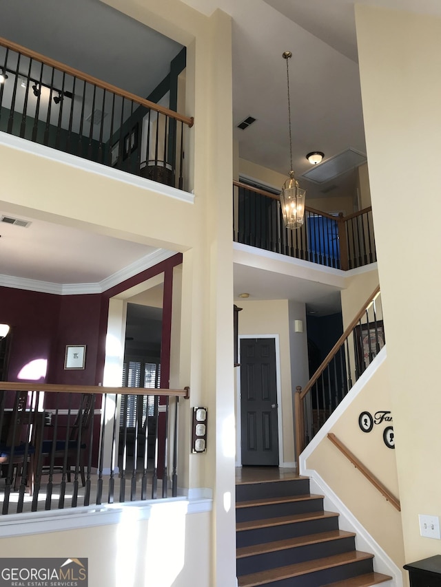 stairs with a notable chandelier and a towering ceiling