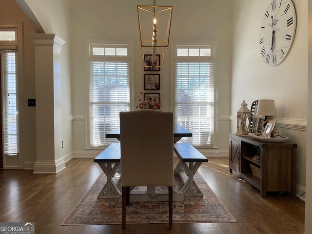 dining room featuring dark hardwood / wood-style floors, a chandelier, and ornate columns