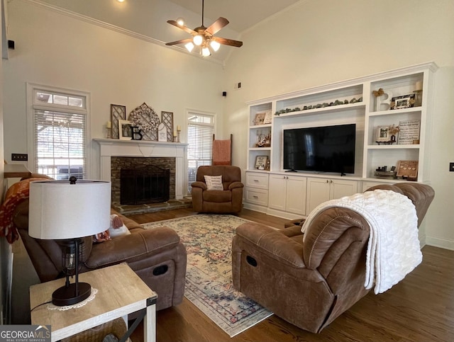 living room featuring a stone fireplace, high vaulted ceiling, ornamental molding, dark hardwood / wood-style flooring, and ceiling fan