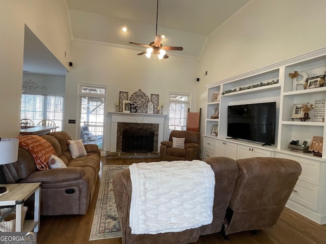 living room featuring a stone fireplace, dark wood-type flooring, high vaulted ceiling, and ceiling fan