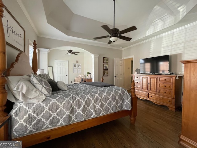 bedroom featuring crown molding, dark wood-type flooring, ceiling fan, a tray ceiling, and ornate columns