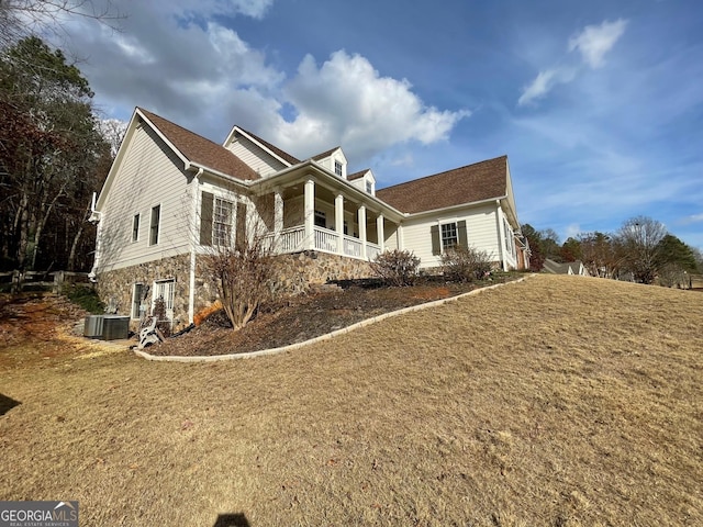 view of side of property with a porch, a yard, and central air condition unit