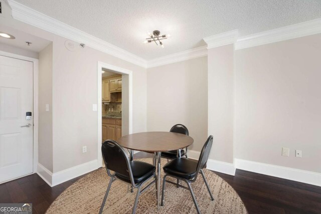 dining room featuring dark hardwood / wood-style flooring, a textured ceiling, and ornamental molding