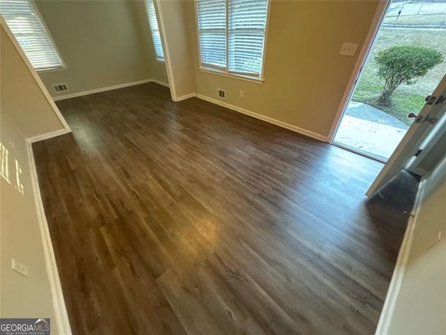 empty room with a healthy amount of sunlight and dark hardwood / wood-style floors