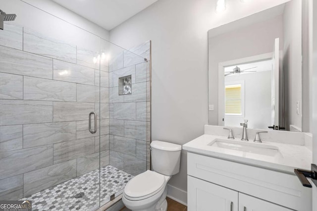 bathroom with vanity, toilet, ceiling fan, and a shower with shower door