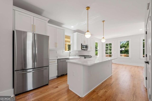 kitchen featuring pendant lighting, a center island, stainless steel appliances, and white cabinetry