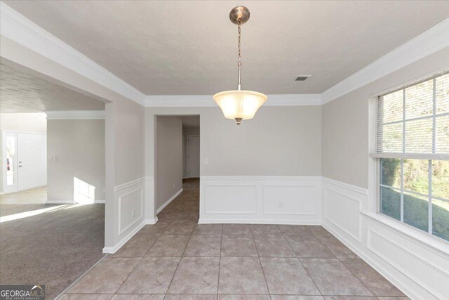 unfurnished dining area featuring light carpet, crown molding, and a textured ceiling