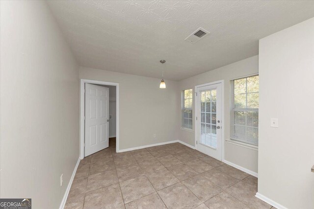unfurnished dining area featuring light tile patterned floors and a textured ceiling