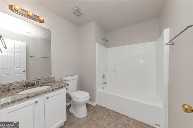 full bathroom featuring tile patterned flooring, bathing tub / shower combination, a textured ceiling, toilet, and vanity