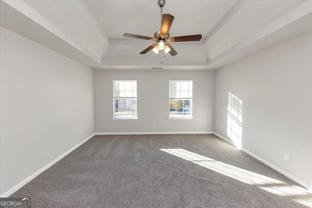 carpeted empty room with a tray ceiling and ceiling fan