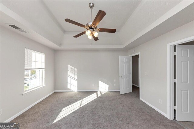 unfurnished bedroom with carpet floors, a raised ceiling, and ceiling fan