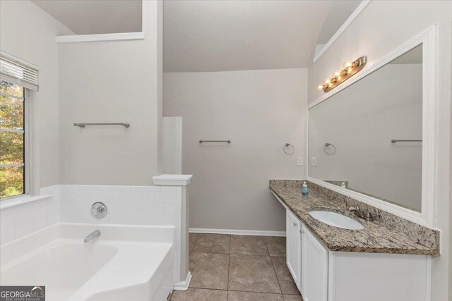 bathroom featuring tile patterned flooring, vanity, a textured ceiling, and a washtub