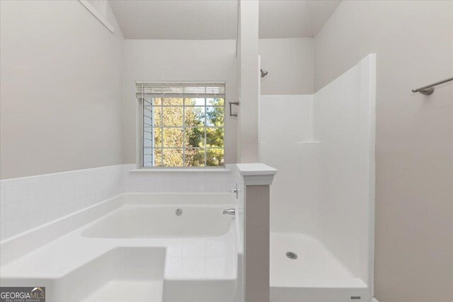 bathroom with a textured ceiling and independent shower and bath