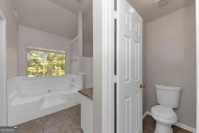 bathroom with tile patterned flooring, vanity, toilet, and a tub