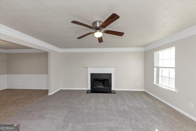 unfurnished living room featuring carpet floors, ceiling fan, and ornamental molding