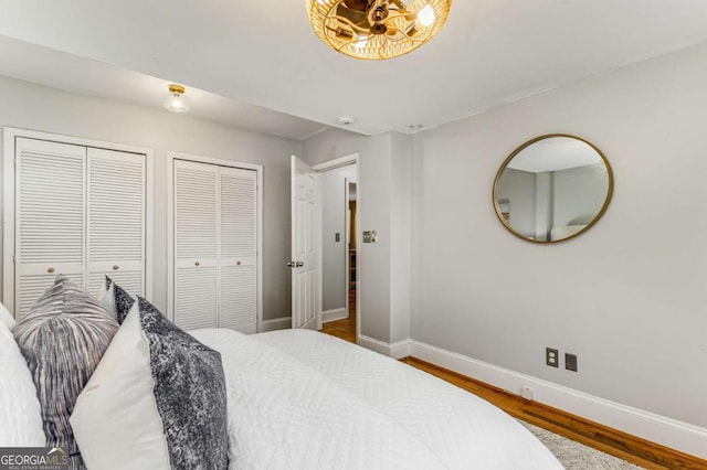 bedroom with multiple closets and wood-type flooring